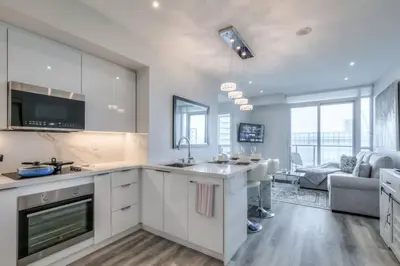 a kitchen with white cabinets and a living room at Down Town CN Tower View 2BR Condo with Balcony and WiFi in Toronto