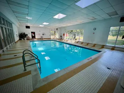 a large swimming pool with blue water in a building at Lower Penthouse Suite with Pools & Sunset Views in Toronto