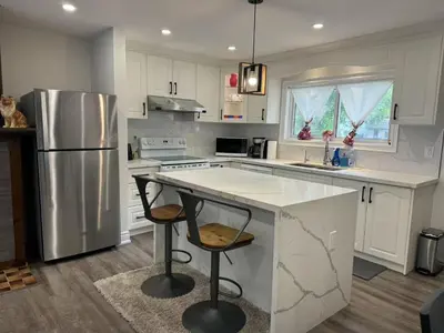 a kitchen with a refrigerator and a counter with two bar stools at Comfortable waterfront vacation Keswick in Georgina