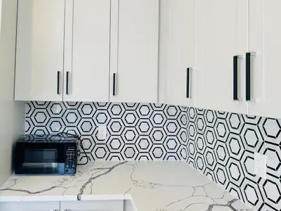 a kitchen with white cabinets and a counter with a microwave at Beautiful Brand New House in Keswick 8 guests in Georgina
