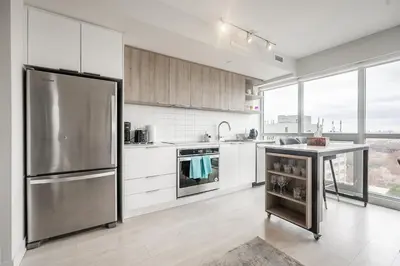 a kitchen with a stainless steel refrigerator and white cabinets at Panoramic view Condo 2 BR 2 BA Free parking in Toronto
