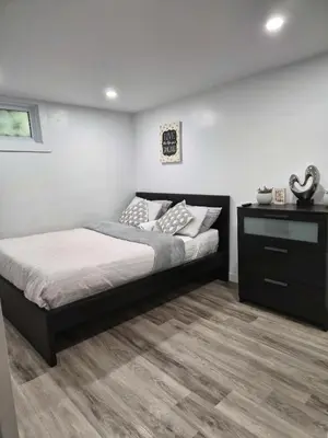 a bedroom with a large bed and a dresser at Equipped Basement Great Location in London