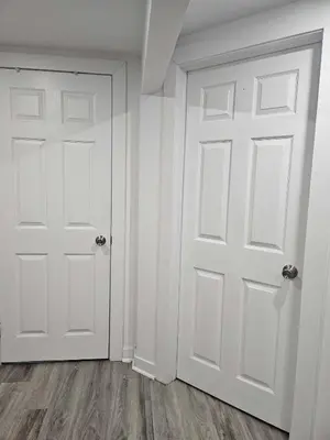an empty room with white doors and wood floors at Equipped Basement Great Location in London