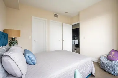 a bedroom with a large white bed with blue pillows at Stylish 2 BR & Den 2BA with Free Parking in Toronto