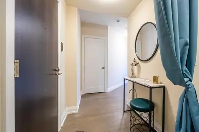 a hallway with a mirror and a table with a stool at Stylish 2 BR & Den 2BA with Free Parking in Toronto