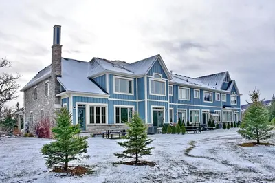 a large blue house with trees in front of it at Blue Mountain Village Townhome 4 Bedroom with Shuttle & Pool in Blue Mountains