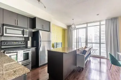 a kitchen with stainless steel appliances and a large window at Classic 1BR & Den Apartment in Downtown Gym Pool in Toronto