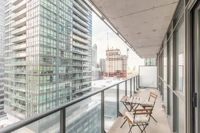 a balcony with two chairs and a table at Classic 1BR & Den Apartment in Downtown Gym Pool in Toronto