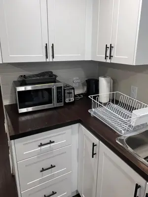 a kitchen with white cabinets and a microwave at Bright & Cozy Bankfield Stay in Toronto