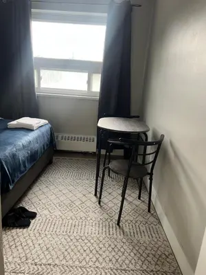 a small table and chair in a small room with a window at Modern Suite, 1 Guest Room in St. Catharines