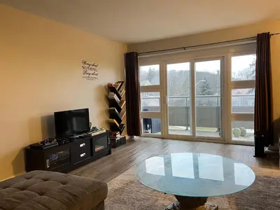 a living room with a glass table and a tv at Modern Suite, 1 Guest Room in St. Catharines