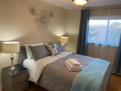 a bedroom with a bed with a lamp and a window at Bright 2 BR pet friendly, KING bed, WiFi,2 parking in Kitchener