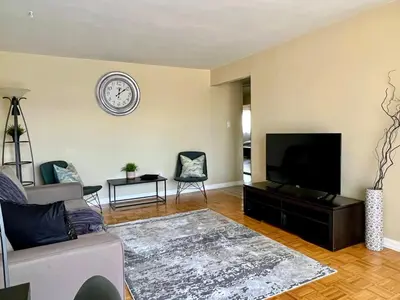 a living room with a couch and a clock on the wall at Bright 2 BR pet friendly, KING bed, WiFi,2 parking in Kitchener