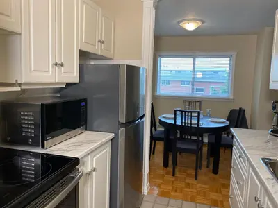 a kitchen with a stainless steel refrigerator and a table at Bright 2 BR pet friendly, KING bed, WiFi,2 parking in Kitchener