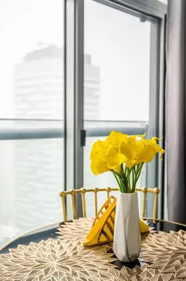 a vase of yellow flowers sitting on a table at Sunshiny 1 BD 61st Floor Outstanding View in Toronto