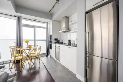 a kitchen with a table and a stainless steel refrigerator at Sunshiny 1 BD 61st Floor Outstanding View in Toronto