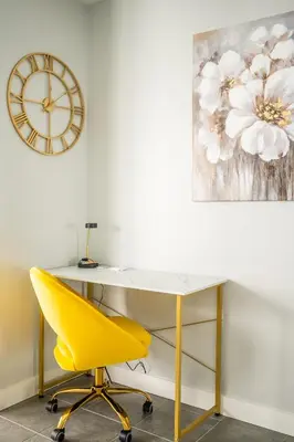 a desk with a yellow chair and a clock on a wall at Sunshiny 1 BD 61st Floor Outstanding View in Toronto