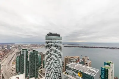 a tall building next to a body of water at Sunshiny 1 BD 61st Floor Outstanding View in Toronto