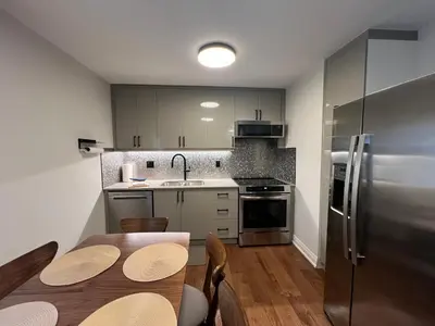 a kitchen with a table and a stainless steel refrigerator at Adrian's Suites 2 Bedroom FamilySuite in Wasaga Beach