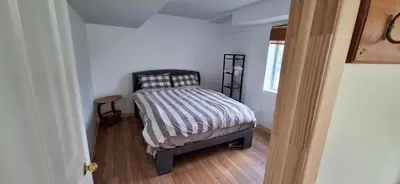 a small bedroom with a bed with a striped comforter at Century House on Quarter acre lot in Acton