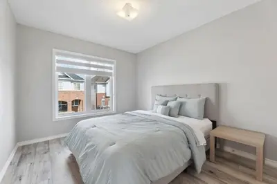 a white bedroom with a bed and a window at The Devineridge Executive House in Ajax