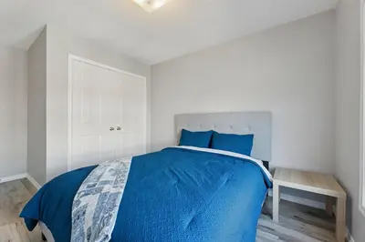 a bedroom with a bed with a blue comforter at The Devineridge Executive House in Ajax