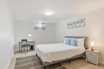 a white bedroom with a bed and a desk at Stewarts Place Newly Renovated Basement City Apartment in Hamilton