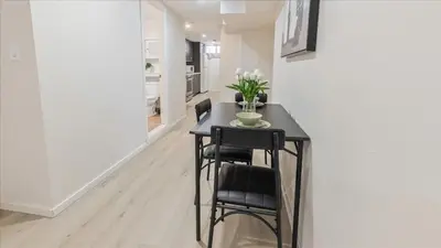 a black table with two chairs and a vase of flowers at Stewarts Place Newly Renovated Basement City Apartment in Hamilton