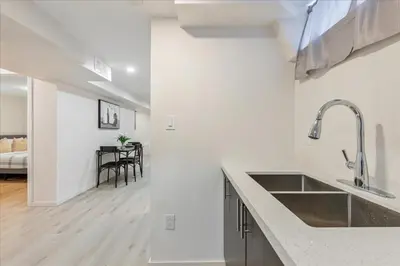 a white kitchen with a sink and a table at Stewarts Place Newly Renovated Basement City Apartment in Hamilton