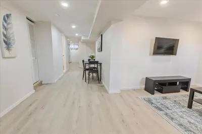a living room with white walls and a table and chairs at Stewarts Place Newly Renovated Basement City Apartment in Hamilton