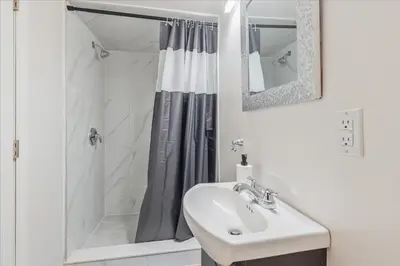 a white bathroom with a shower and a sink at Stewarts Place Newly Renovated Basement City Apartment in Hamilton