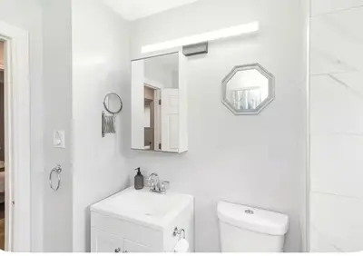 a bathroom with a toilet and a sink and a mirror at Quaint and Stylish UPPER level 3-bed bungalow in Hamilton, ON in Hamilton