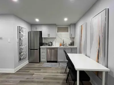 a kitchen with a table and a stainless steel refrigerator at Elegant Oakville Town Residece in Oakville