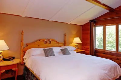 a bedroom with a white bed with two tables and two lamps at Eganridge Resort, Golf Club & Spa in Bobcaygeon