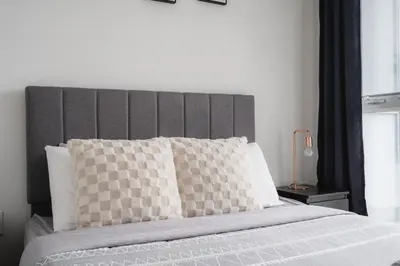 a bed with a gray headboard and white pillows at Downtown Toronto luxury condos in Toronto