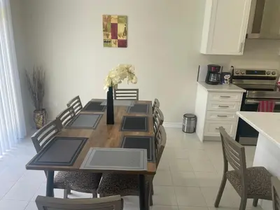 a dining room table with chairs and a vase with flowers at New 3 Bedroom 2 Bathroom Home in West Niagara in Thorold