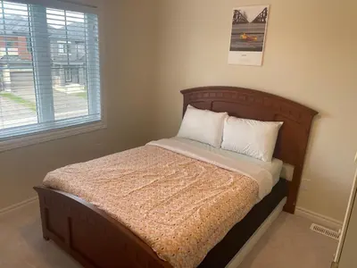a bed with a wooden headboard in a room with a window at New 3 Bedroom 2 Bathroom Home in West Niagara in Thorold
