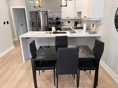 a kitchen with a large white island with black chairs at The Millertime Experience in Brantford