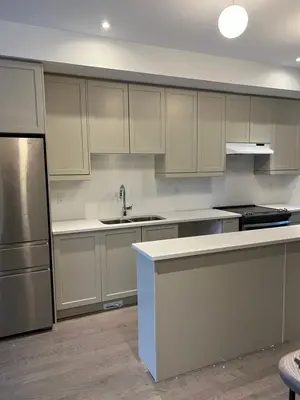 a kitchen with white cabinets and a stainless steel refrigerator at Bowmanville Room in Bowmanville
