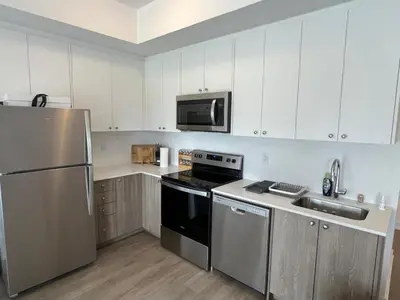 a kitchen with white cabinets and a stainless steel refrigerator at Stylish 2-Story Condo with Balcony in Kitchener