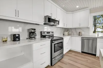 a kitchen with white cabinets and a stove top oven at Pet friendly- Crystal Water fishing Family Retreat in Havelock