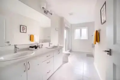 a white bathroom with two sinks and a shower at Severn Woodland in Severn