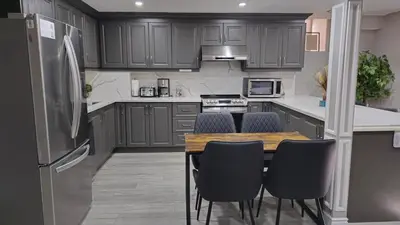 a kitchen with gray cabinets and a wooden table with chairs at 3 bdrm 3 bath bsmt Brampton Toronto, Sleeps 16 in Brampton