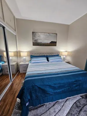 a bedroom with a large bed with a blue bedspread at King Comfort Retreat in Peterborough