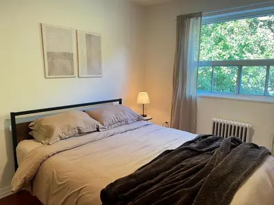 a bedroom with a large bed with a window at Upper Beaches Apartment in Toronto
