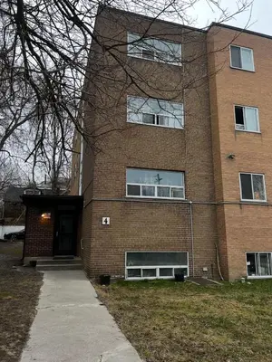 a large brick building with a door and a sidewalk at Upper Beaches Apartment in Toronto
