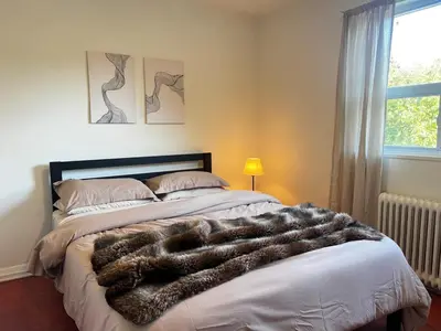 a bedroom with a bed with a faux fur blanket at Upper Beaches Apartment in Toronto