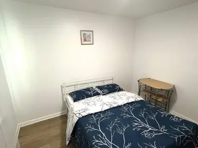 a bedroom with a bed with a blue and white comforter at 9mins airport 1 min to shopping mall in Toronto
