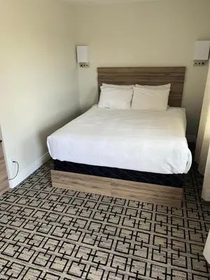 a bedroom with a bed with a wooden frame and a white bed sidx sidx sidx at Sunrise Motel in Owen Sound