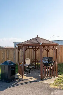 a wooden gazebo with a grill and a table at Sunrise Motel in Owen Sound